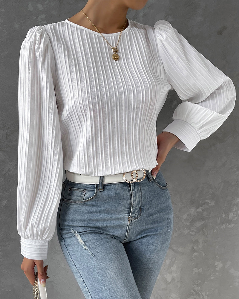 Blusa primaveral de mujer con cuello redondo, mangas largas abullonadas y corte holgado.