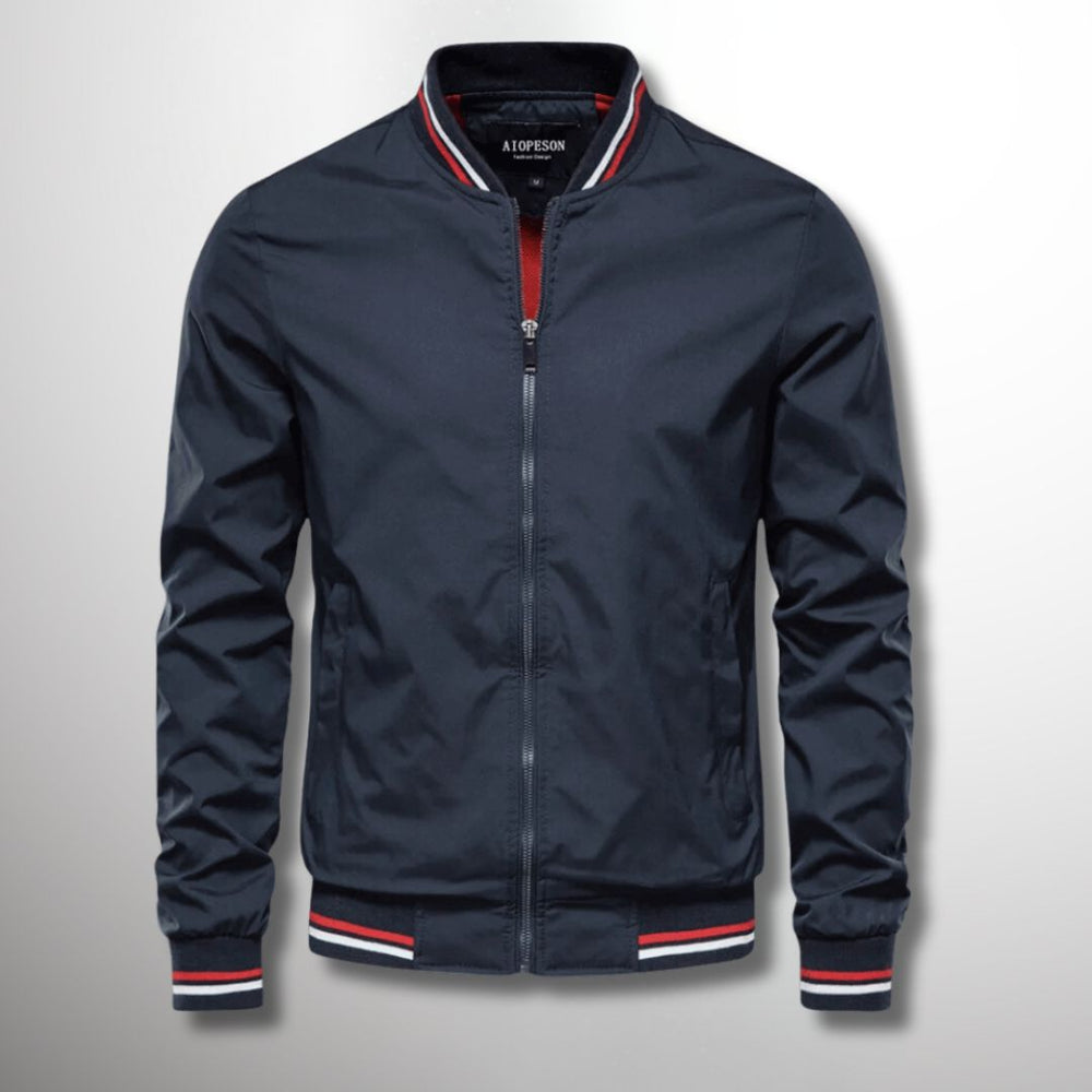 Giacca bomber blu scuro con zip, colletto e polsini a righe rosse e bianche, stile casual, moda uomo, abbigliamento autunnale.