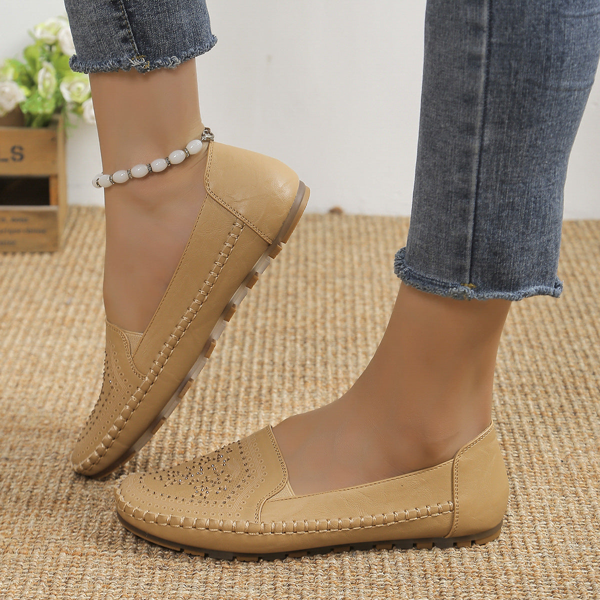 Scarpe mocassini beige da donna in pelle, con dettagli traforati, indossate con jeans. Calzature comode e alla moda per look casual.