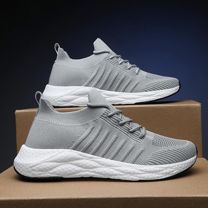 Scarpe da ginnastica grigie su scatole di cartone, design moderno e traspirante, suola bianca ammortizzata. Scarpe sportive leggere e comode.