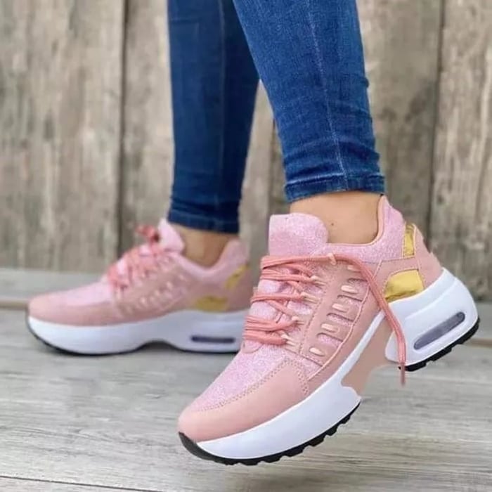 Scarpe da ginnastica rosa con dettagli dorati, suola bianca spessa, indossate con jeans aderenti. Sneakers moda donna, stile casual e sportivo.