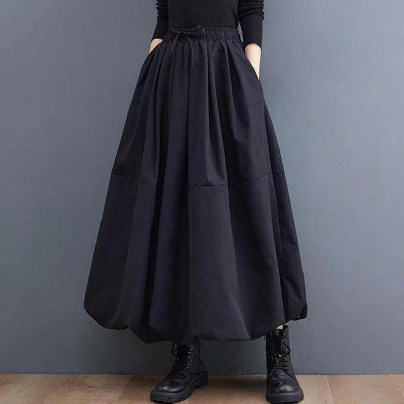 Gonna lunga nera in tessuto ampio, indossata con stivali neri. Moda donna autunno inverno, stile casual chic.