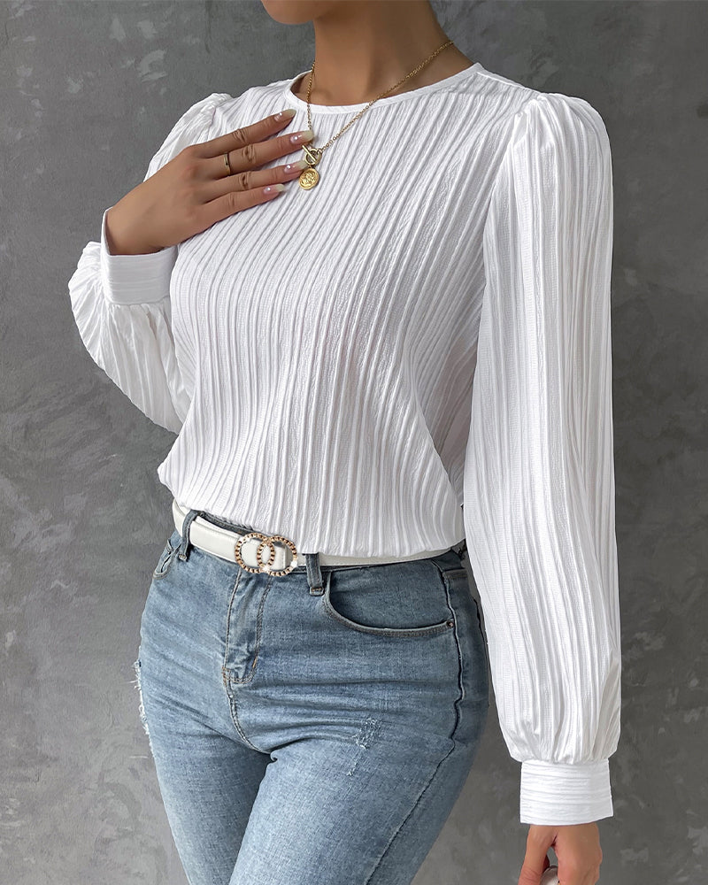Blusa primaveral de mujer con cuello redondo, mangas largas abullonadas y corte holgado.