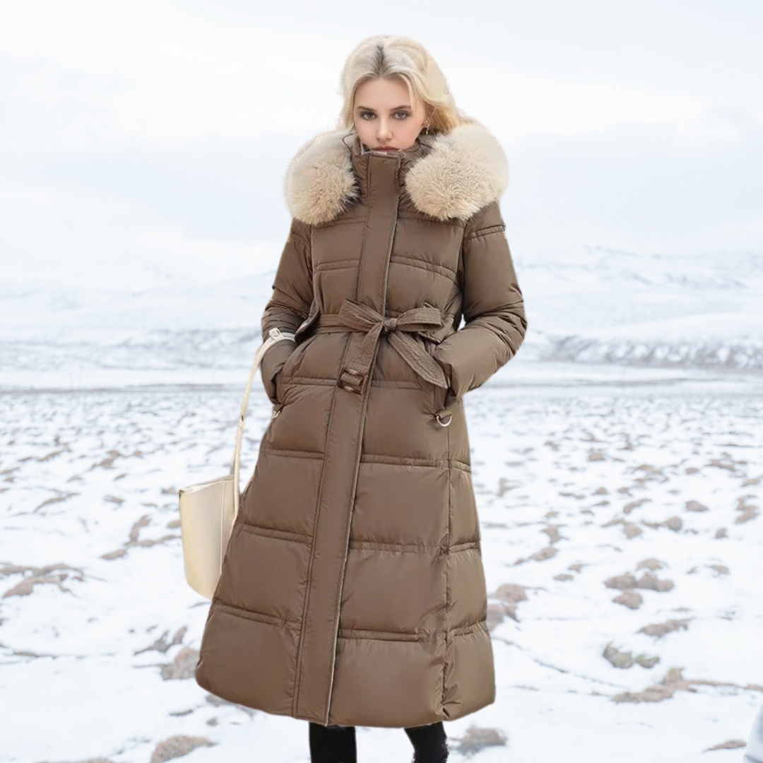 Donna in cappotto invernale marrone con cappuccio in pelliccia, paesaggio innevato sullo sfondo. Moda inverno, abbigliamento caldo, stile elegante.