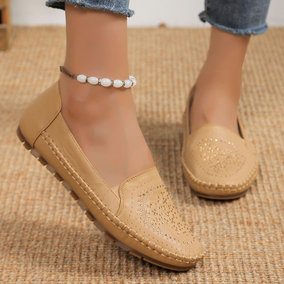 Scarpe mocassini beige da donna in pelle, con dettagli traforati, indossate con jeans. Scarpe comode e alla moda, ideali per look casual.
