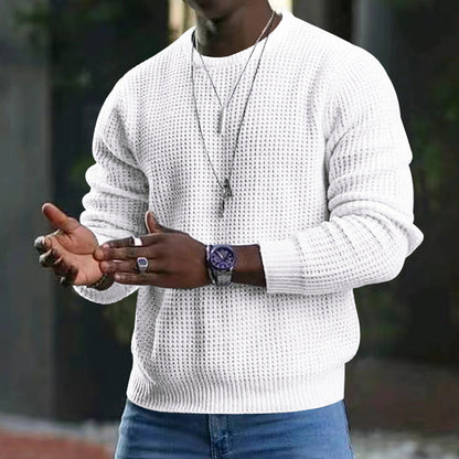 Uomo con maglione bianco a maglia, orologio nero e collana, in posa all'aperto. Moda maschile casual, accessori eleganti, stile moderno.
