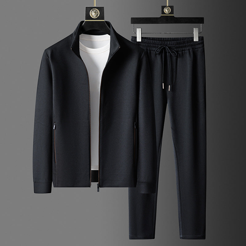 Completo sportivo uomo nero, giacca con zip e pantaloni con coulisse, su sfondo grigio. Abbigliamento casual elegante, moda maschile.