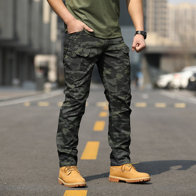 Uomo in pantaloni mimetici e stivali gialli su strada urbana. Moda maschile casual, abbigliamento militare, stile urbano.
