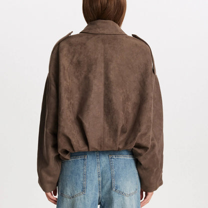 Donna di spalle con giacca marrone scamosciata e jeans blu. Moda autunnale, abbigliamento casual, stile urbano.