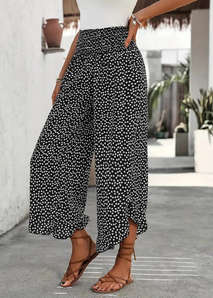 Pantaloni palazzo a pois bianchi e neri, indossati con sandali marroni. Moda estiva casual, outfit elegante per donna.