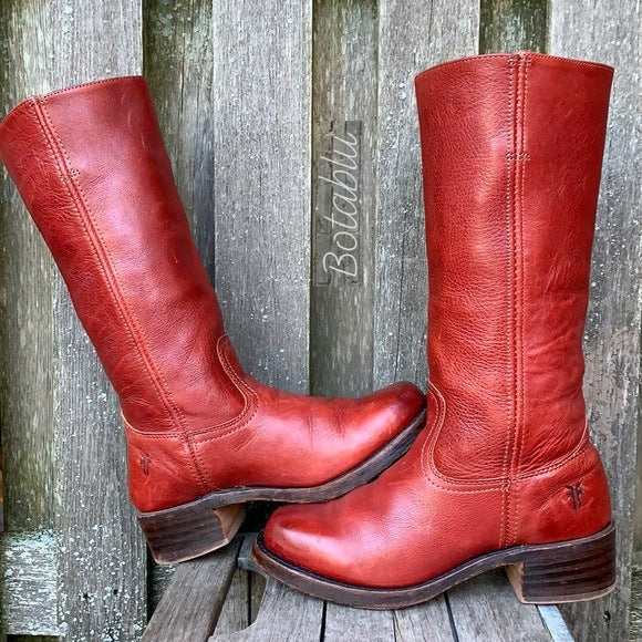 Stivali in pelle rossa vintage su sfondo di legno, design classico, tacco basso, moda retrò, calzature artigianali di qualità.