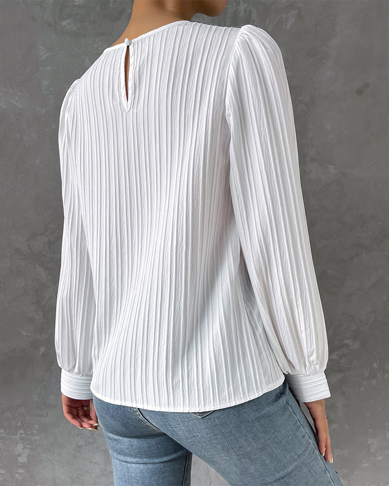 Blusa primaveral de mujer con cuello redondo, mangas largas abullonadas y corte holgado.