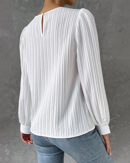 Blusa primaveral de mujer con cuello redondo, mangas largas abullonadas y corte holgado.