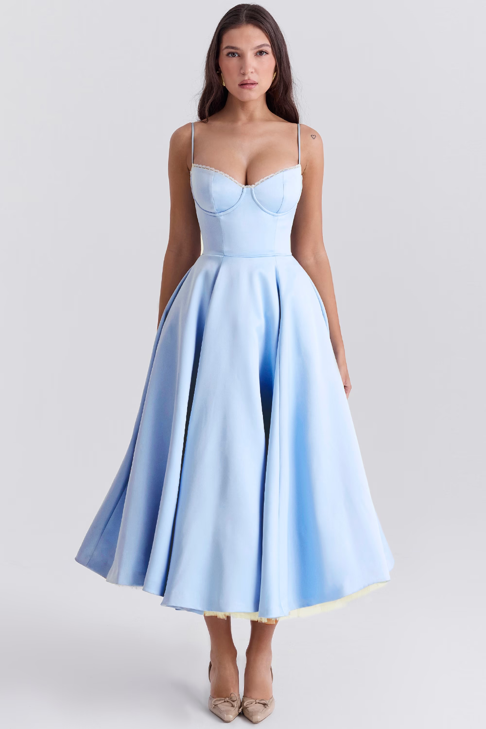 Donna in abito azzurro elegante, scollatura a cuore, gonna ampia, spalline sottili, posa su sfondo neutro. Moda femminile, abbigliamento da sera.