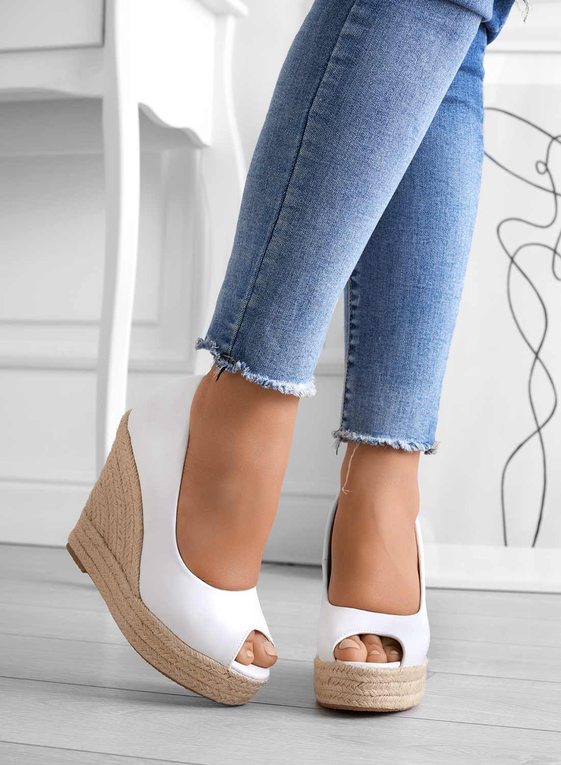 Jeans attillati blu e scarpe con zeppa in corda bianca, stile casual chic, moda donna, pavimento in legno chiaro, sfondo minimalista.