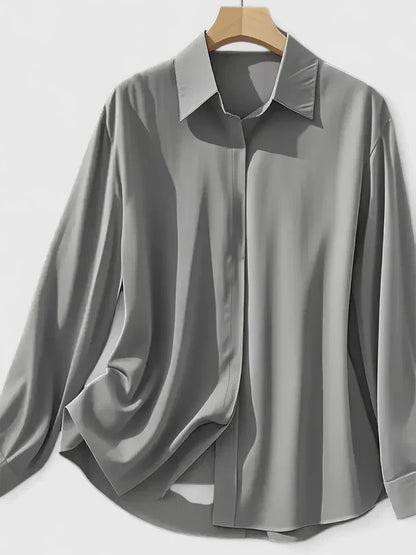 Camicia grigia elegante in seta su appendiabiti, maniche lunghe, colletto classico. Moda uomo, abbigliamento formale, stile sofisticato.