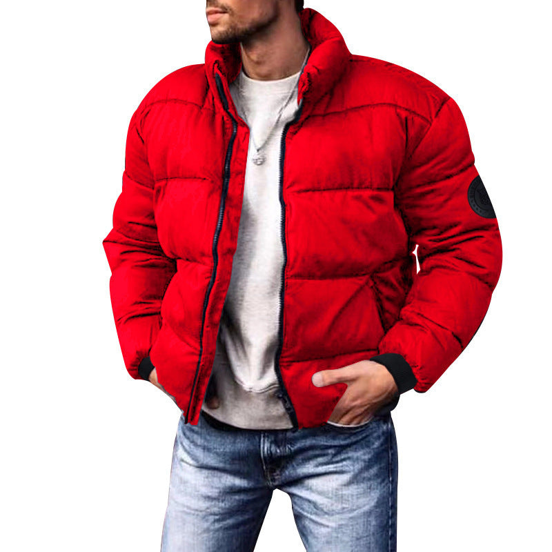 Giacca invernale uomo rossa, imbottita, con zip e colletto alto. Moda casual, ideale per l'inverno. Indossata con jeans e maglietta grigia.