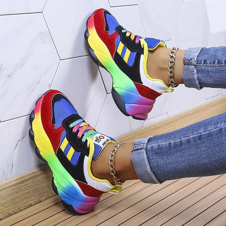 Scarpe da ginnastica multicolore con suola arcobaleno, indossate con jeans. Design moderno e vivace, perfette per uno stile casual e alla moda.