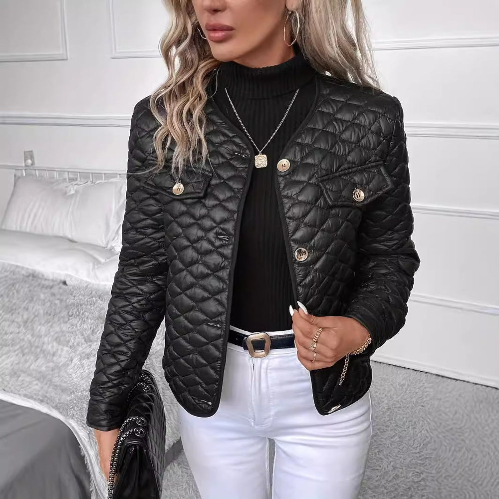 Donna con giacca trapuntata nera, maglia nera e pantaloni bianchi in camera moderna. Moda autunnale, stile elegante, abbigliamento casual chic.