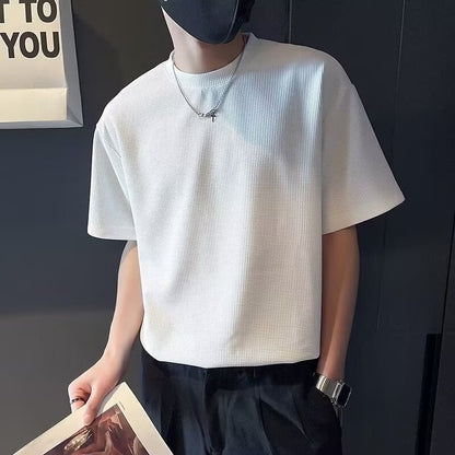 Uomo con maglietta bianca a maniche corte, pantaloni neri, orologio al polso, mascherina nera. Stile casual moderno.