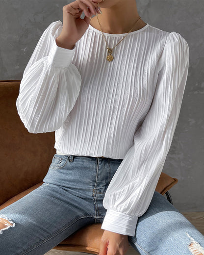 Blusa primaveral de mujer con cuello redondo, mangas largas abullonadas y corte holgado.