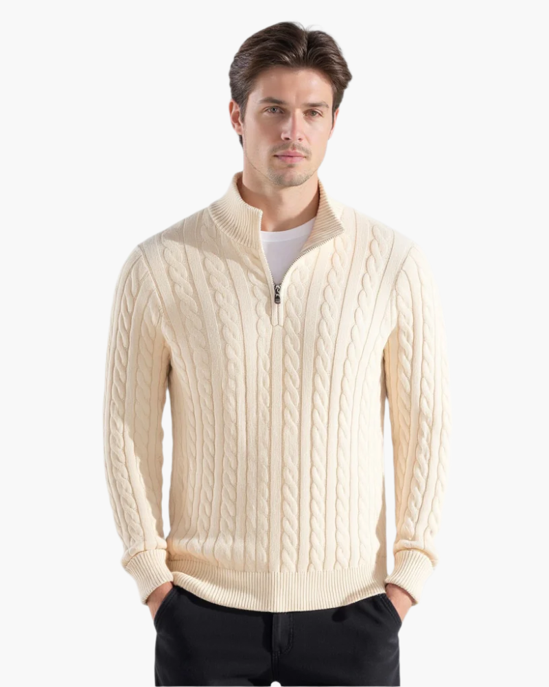Uomo con maglione a trecce color crema, zip frontale, colletto alto, su sfondo bianco. Moda maschile, abbigliamento invernale elegante.