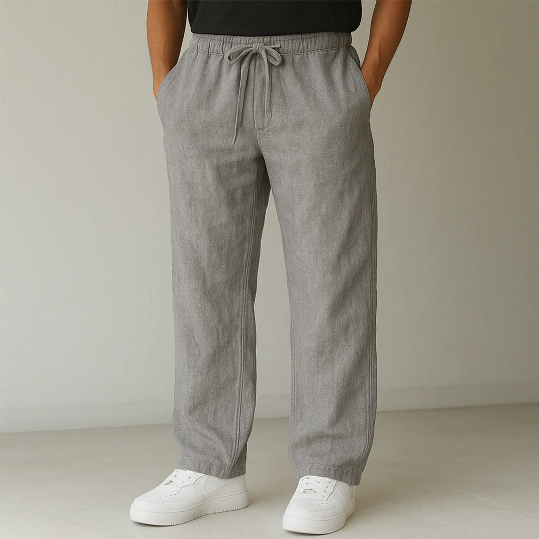 Pantaloni grigi in lino da uomo con coulisse, abbinati a scarpe da ginnastica bianche. Stile casual ed elegante, perfetto per la moda estiva.