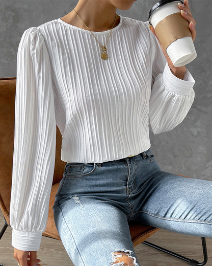 Blusa primaveral de mujer con cuello redondo, mangas largas abullonadas y corte holgado.