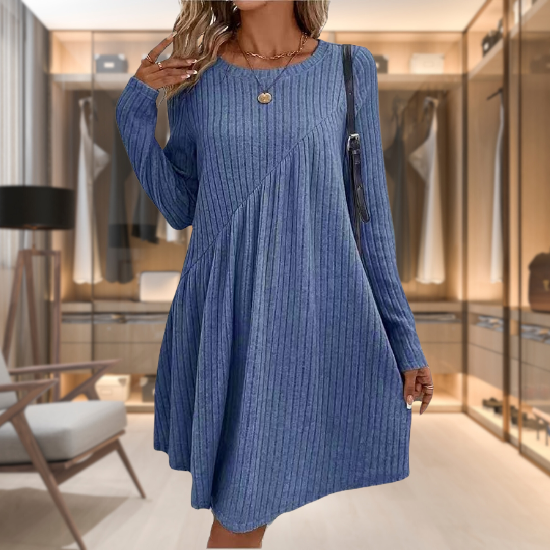 Donna con abito blu a coste, maniche lunghe, in cabina armadio moderna. Moda femminile, abbigliamento casual elegante, tendenza autunno.