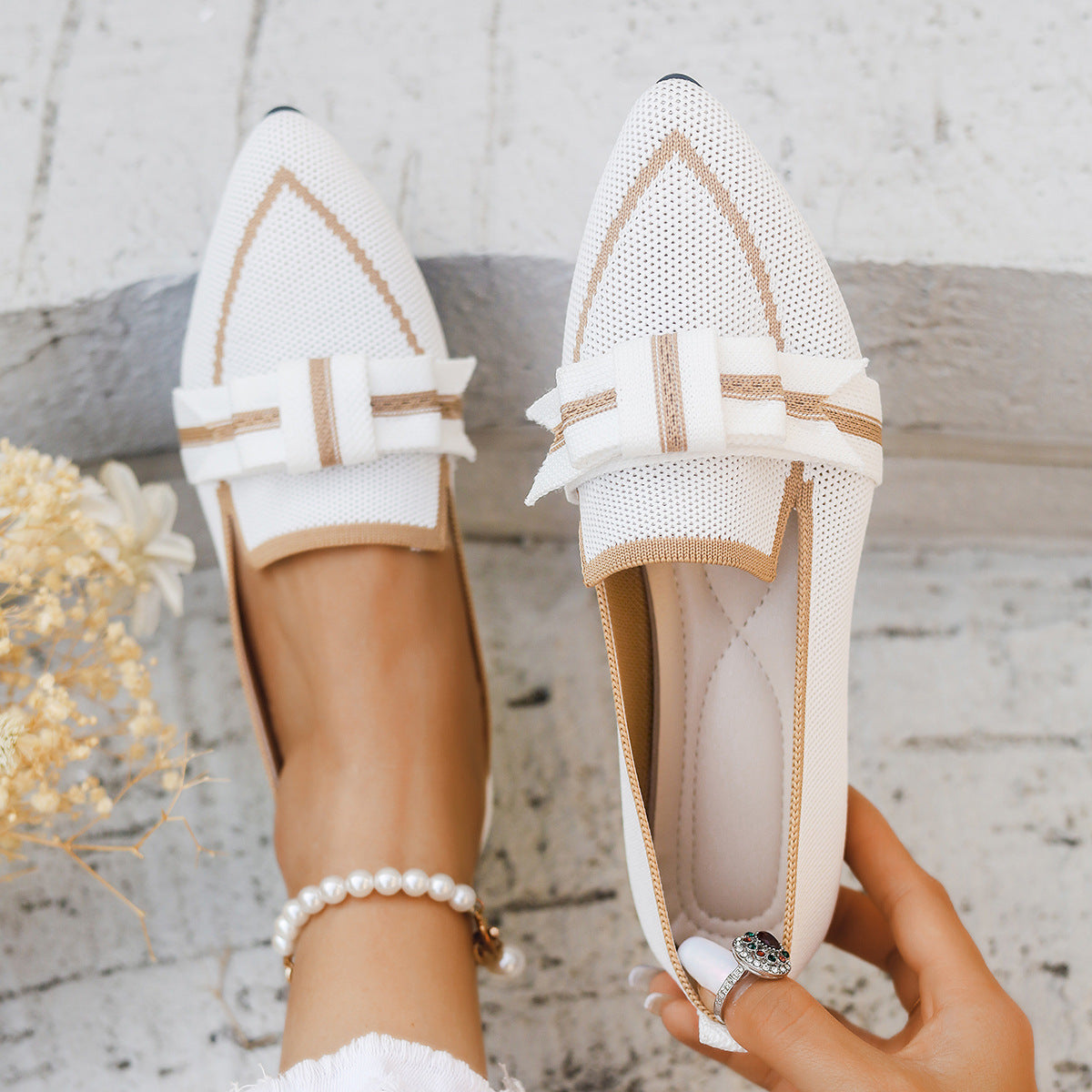 Scarpe eleganti bianche da donna con fiocco, design traforato, indossate su pavimento chiaro. Accessorio moda, calzature estive chic.