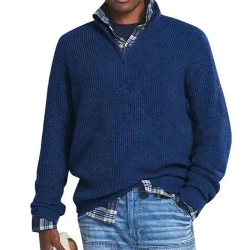 Maglione blu a collo alto con zip, indossato sopra una camicia a quadri, abbinato a jeans casual. Moda uomo autunno inverno, stile casual elegante.