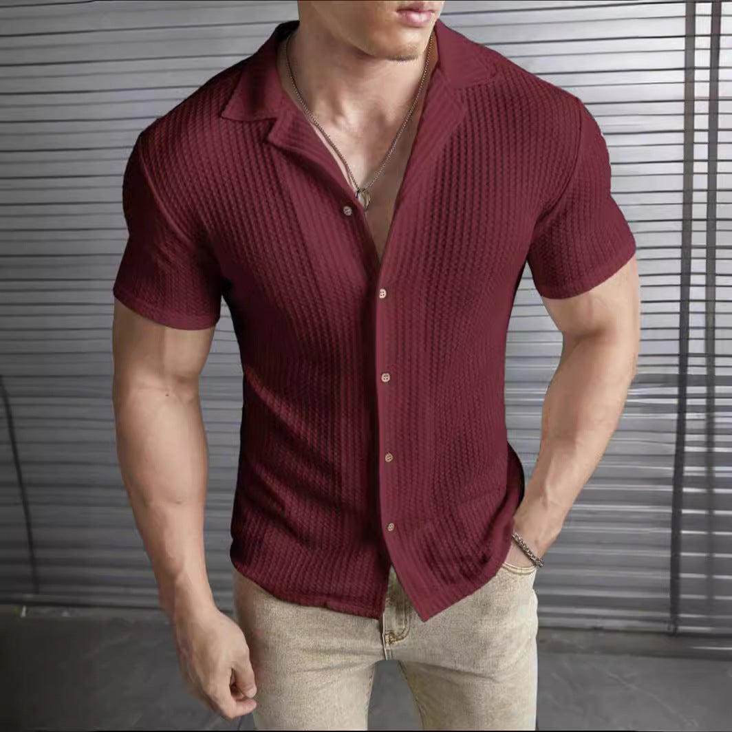 Uomo in camicia rossa a maniche corte, tessuto a coste, davanti a parete metallica. Moda maschile, abbigliamento casual elegante.