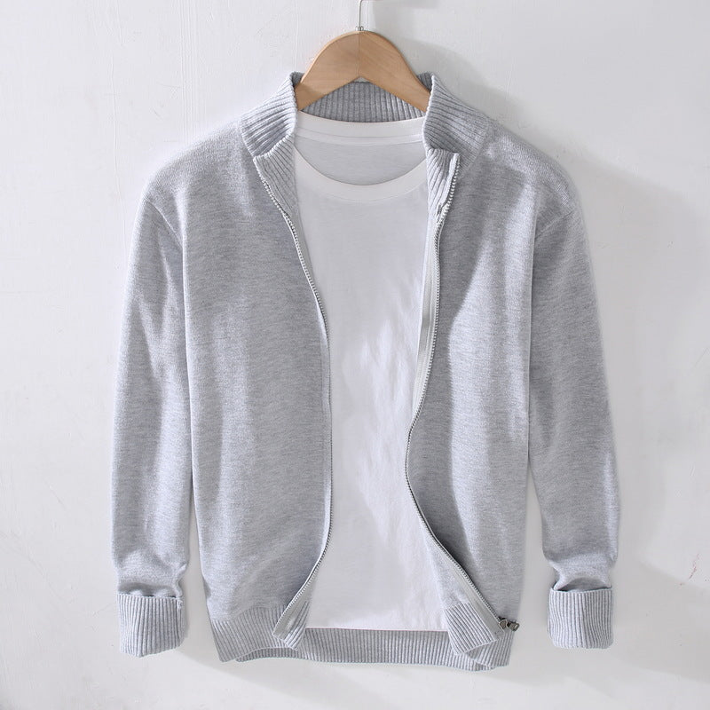 Cardigan grigio chiaro in cotone su gruccia, con zip aperta e maglietta bianca sotto. Moda casual uomo, abbigliamento autunnale elegante.