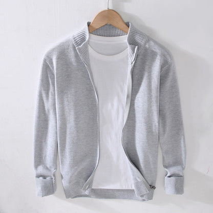 Cardigan grigio chiaro in cotone su gruccia, con zip aperta e maglietta bianca sotto. Moda casual uomo, abbigliamento autunnale elegante.