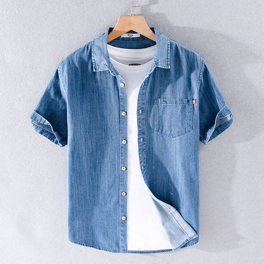 Camicia di jeans blu da uomo su gruccia, con maniche corte e taschino, abbinata a t-shirt bianca. Moda casual, abbigliamento estivo.