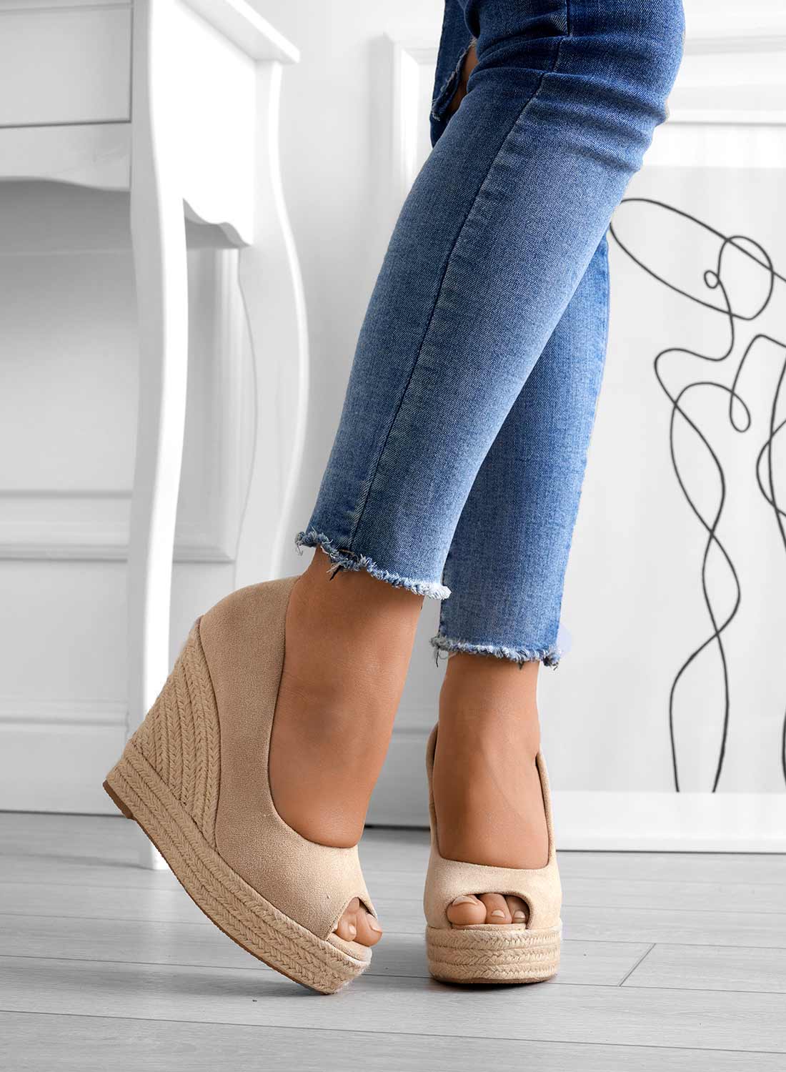 Scarpe con zeppa beige su pavimento in legno, indossate con jeans aderenti. Moda donna, calzature estive eleganti, tendenze scarpe 2023.