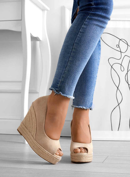 Scarpe con zeppa beige su pavimento in legno, indossate con jeans aderenti. Moda donna, calzature estive eleganti, tendenze scarpe 2023.
