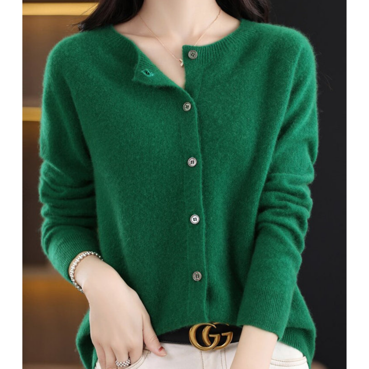Maglione verde in cashmere con bottoni, indossato da una donna. Moda autunnale elegante, abbinato a cintura di lusso. Stile casual chic.