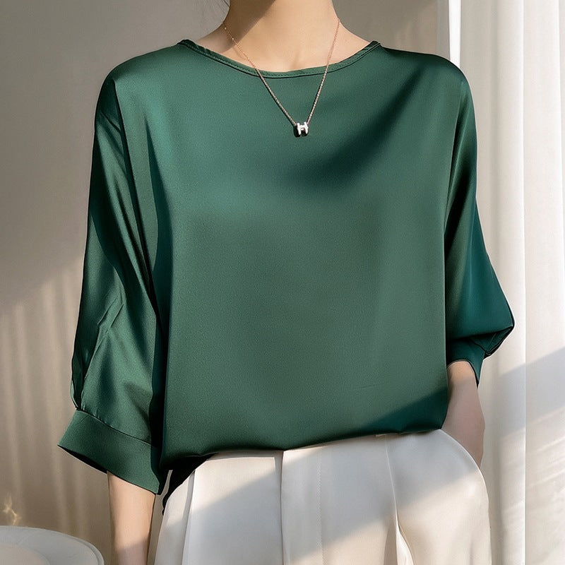 Blusa verde in seta lucida, maniche lunghe, indossata da una donna. Elegante e moderna, perfetta per moda femminile e abbigliamento casual chic.