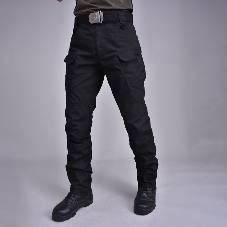 Pantaloni tattici neri con tasche cargo, cintura robusta e stivali militari. Abbigliamento outdoor resistente e funzionale per attività all'aperto.