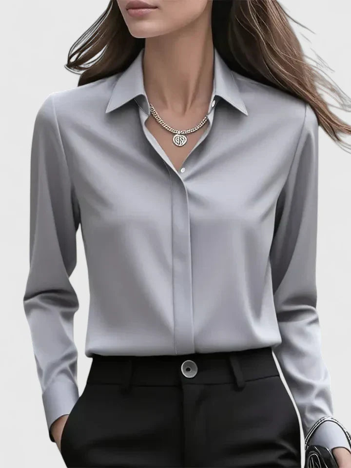 Donna in camicia grigia elegante e pantaloni neri, indossa una collana d'argento. Moda femminile, abbigliamento da ufficio, stile professionale.