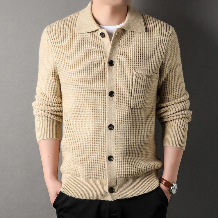 Maglione beige uomo in lana a coste con bottoni neri, taschino frontale, indossato su sfondo grigio. Moda autunnale elegante e casual.