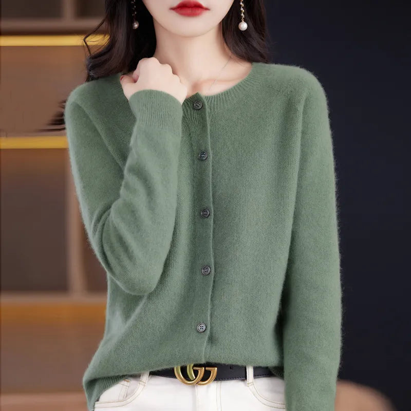 Donna con cardigan verde in cashmere, bottoni frontali, indossa jeans bianchi. Look elegante e casual, moda autunnale femminile.
