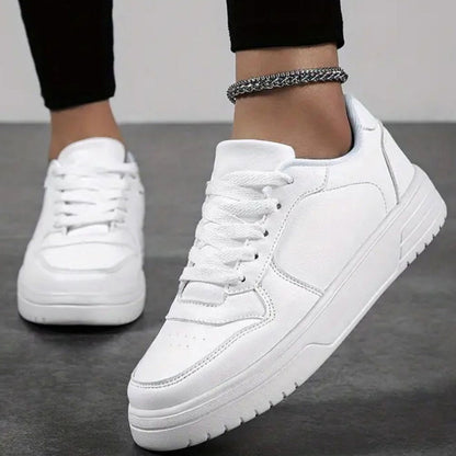 Scarpe da ginnastica bianche su pavimento grigio, indossate con pantaloni neri. Design moderno, suola spessa, perfette per moda casual e sportiva.