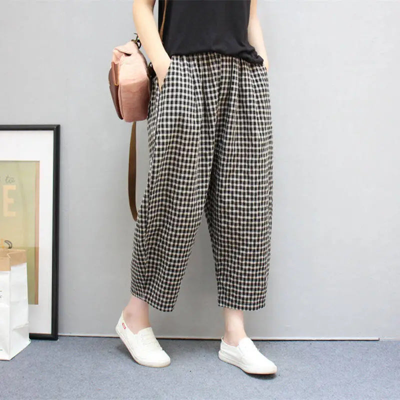 Donna con pantaloni a quadri bianchi e neri, maglietta nera, zaino rosa e scarpe bianche. Moda casual femminile, stile urbano.