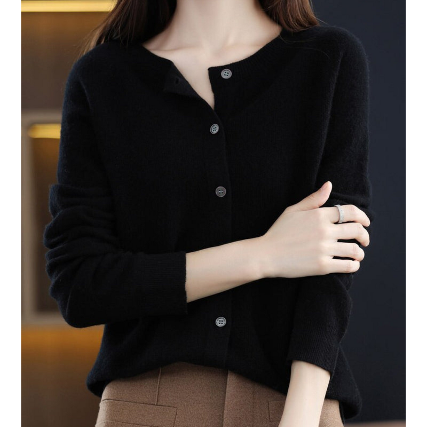 Donna con cardigan nero elegante, abbottonato, su sfondo scuro. Moda autunnale, stile minimalista, abbigliamento casual chic.
