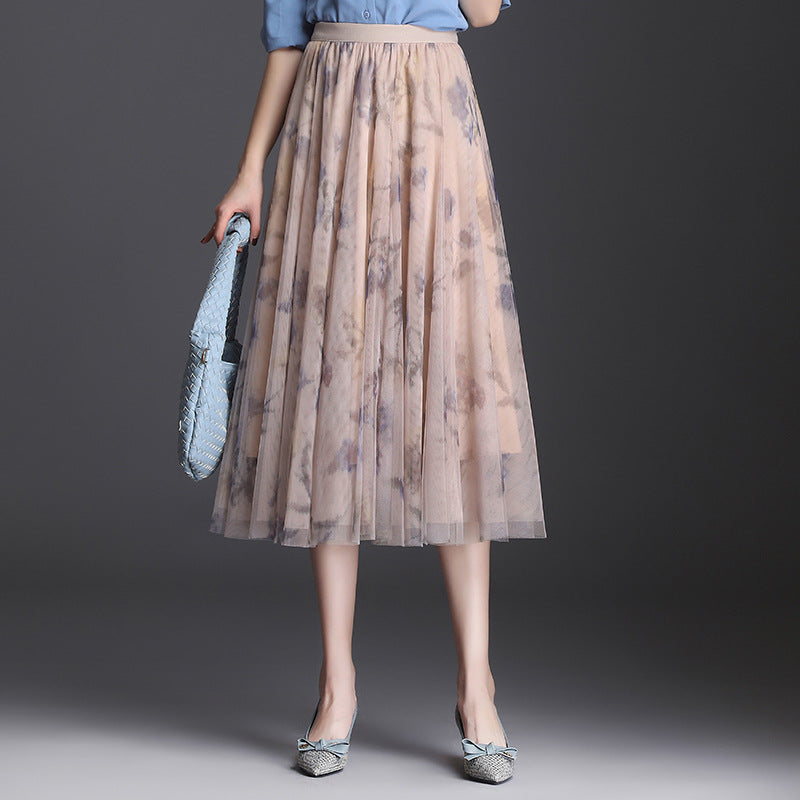 Gonna lunga in tulle floreale beige, abbinata a camicia azzurra e borsa intrecciata blu, moda elegante donna, abbigliamento primaverile.