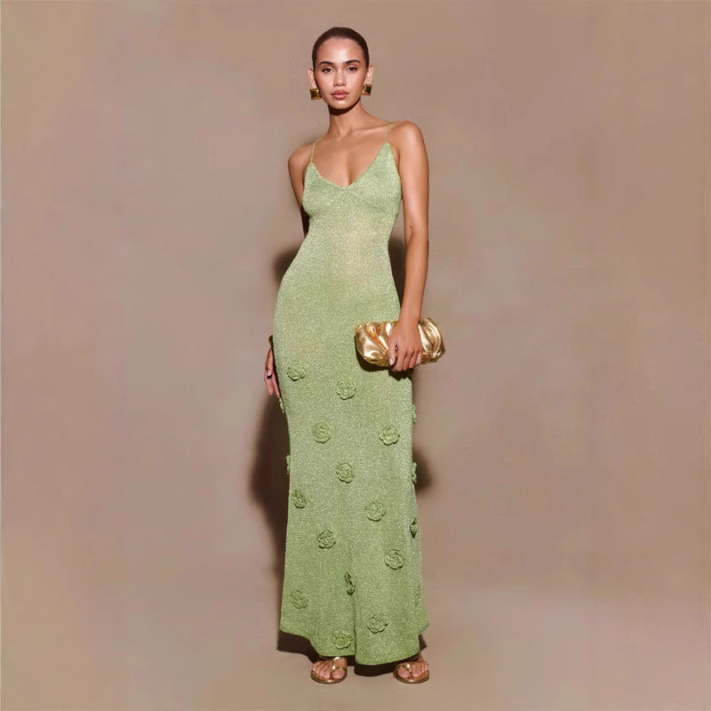 Donna in abito lungo verde con dettagli floreali, borsa dorata e sandali. Moda elegante, abbigliamento da sera, stile sofisticato.