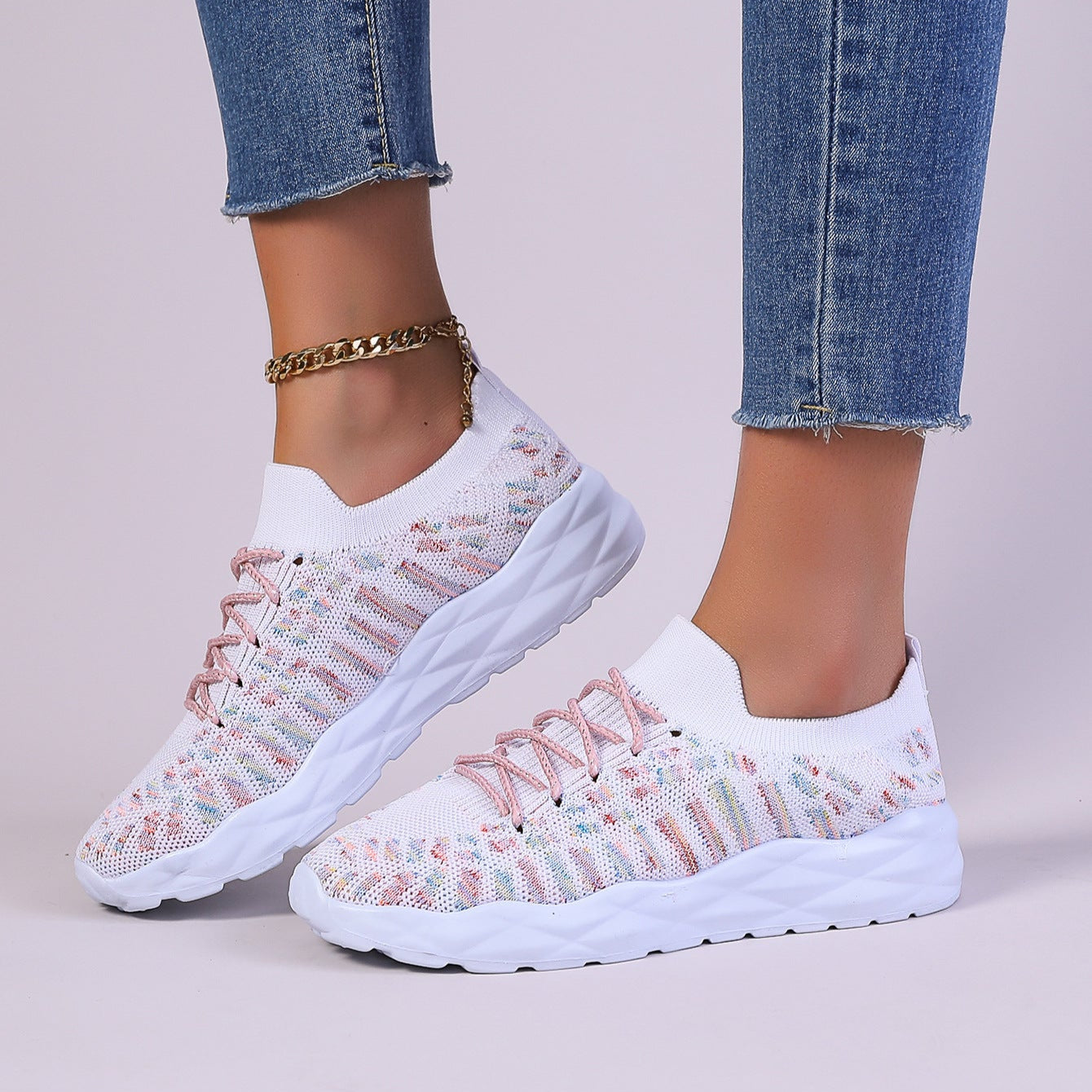 Scarpe da ginnastica bianche con dettagli rosa, suola spessa, indossate con jeans aderenti e cavigliera dorata. Moda casual donna, calzature trendy.