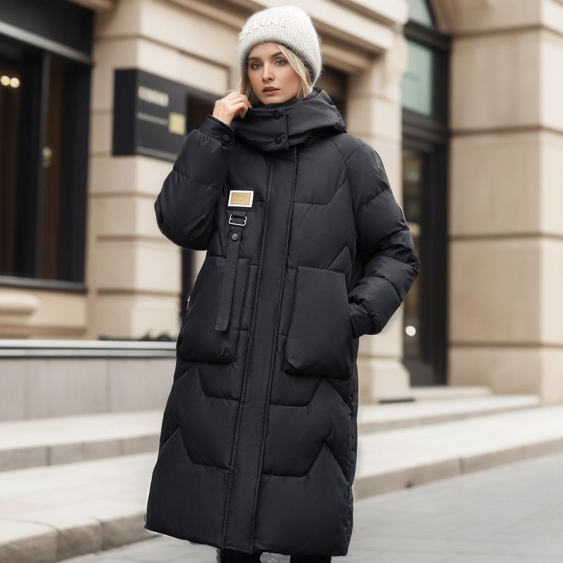 Donna con cappotto lungo nero invernale, cappello di lana grigio, cammina in città. Moda invernale, abbigliamento caldo, stile urbano elegante.